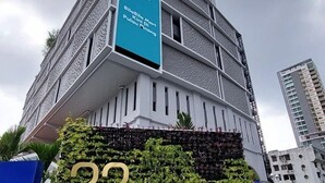 Un edificio moderno con un cartello che riporta la scritta "22 MACAISTERZ" e un cartellone blu con del testo.