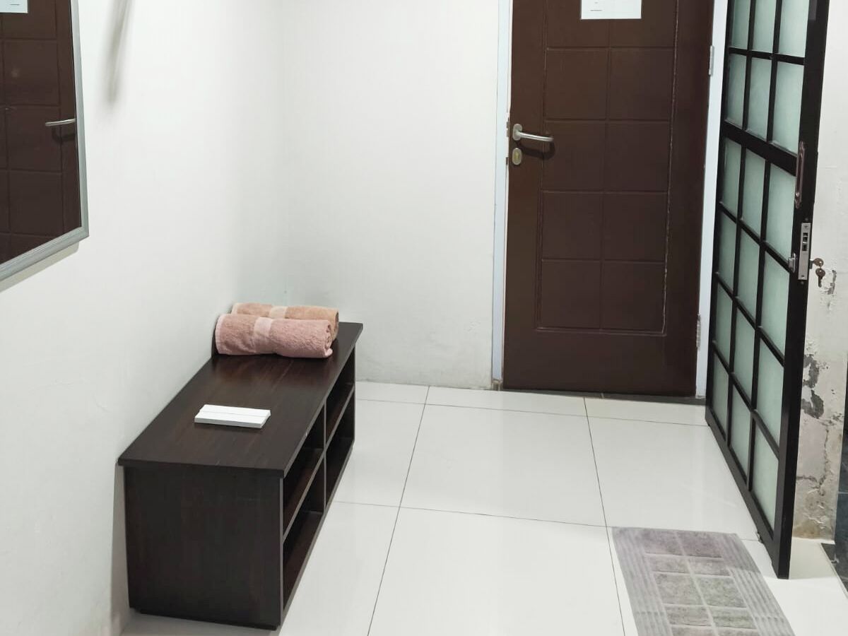 A hallway with a dark wooden bench, a brown door, and a glass door with a metal frame.