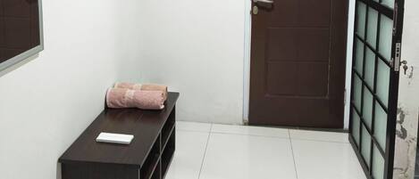 A hallway with a dark wooden bench, a brown door, and a glass door with a metal frame.