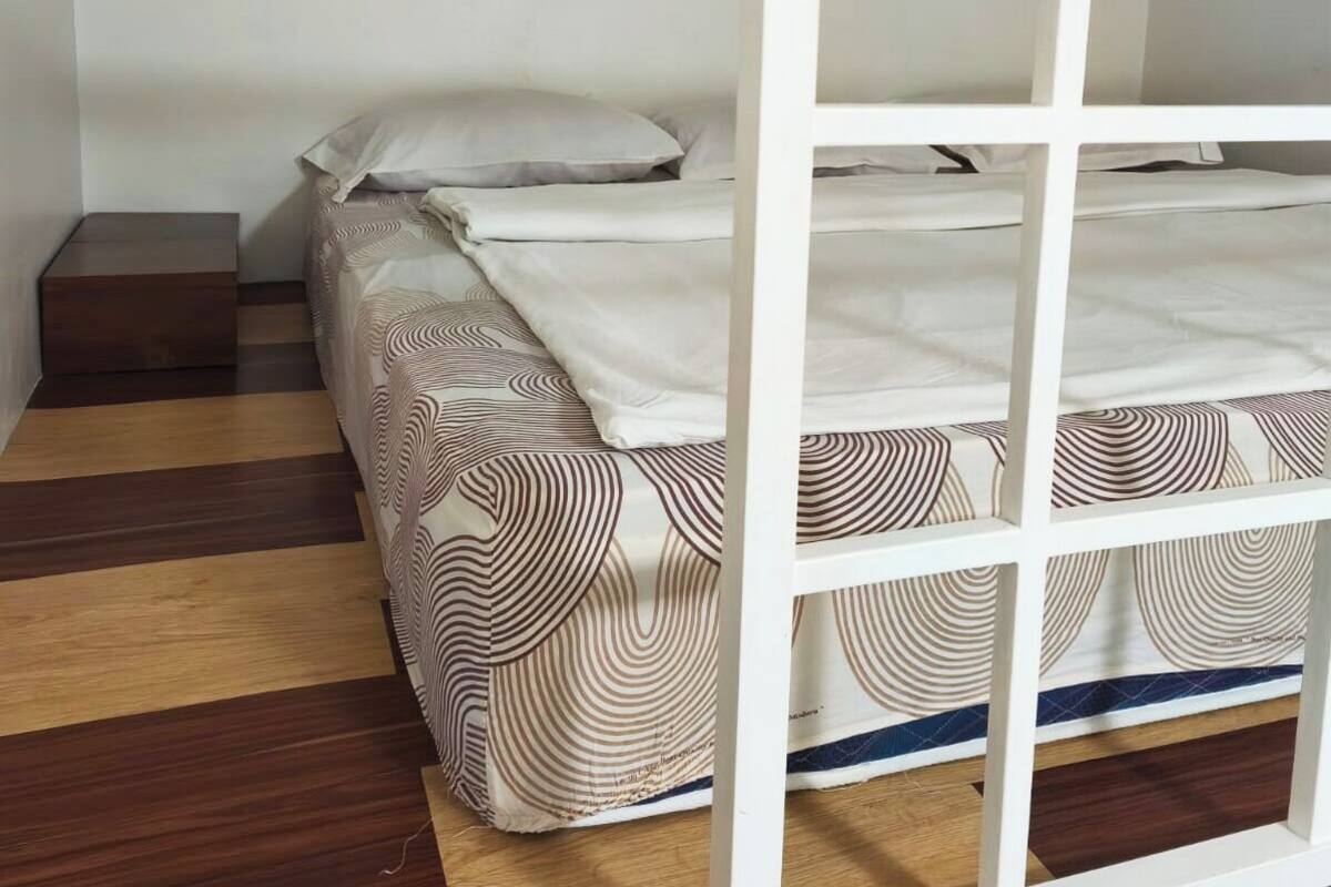 A room with a bed, a wooden nightstand, and a patterned bedspread.