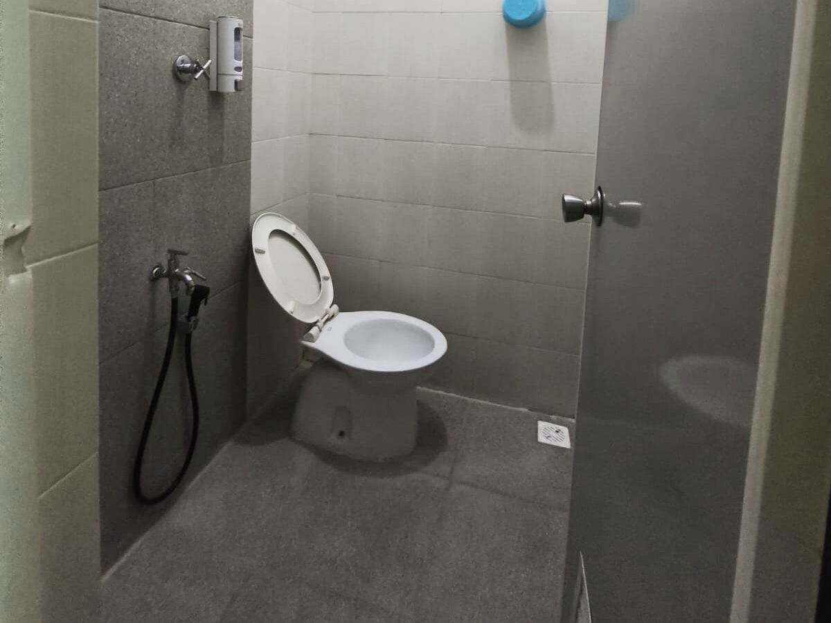 Un baño pequeño y cerrado con un inodoro, un secador de manos y dispensador de toallas de papel.