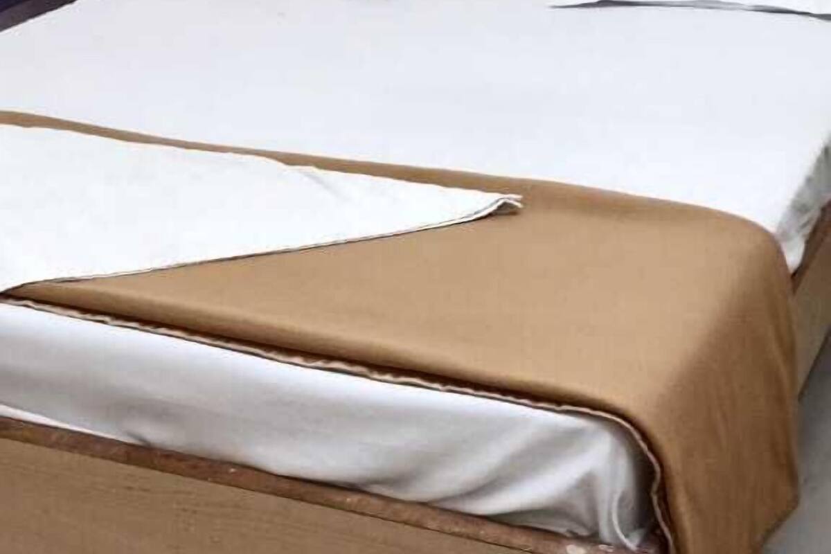 Una cama individual con estructura de madera y ropa de cama blanca.