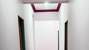 A corridor with white walls and a tiled floor, leading to a door at the end. - Vaishali Lodge (Pune)