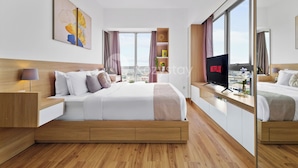 A modern hotel room with a large bed, wooden headboard, bedside tables, a TV, and a window with a city view.