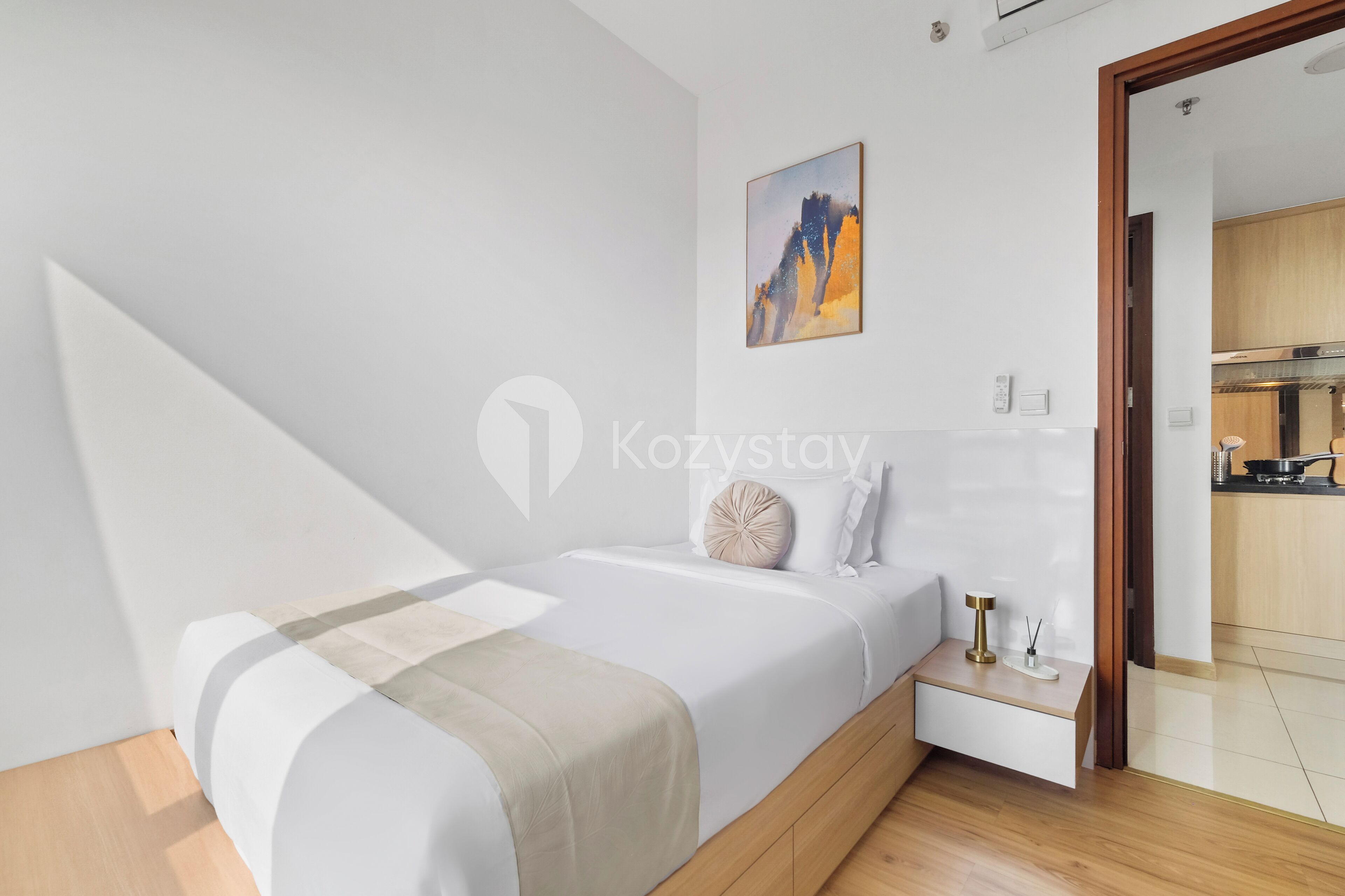 A modern bedroom with a bed, bedside table, and a painting on the wall.