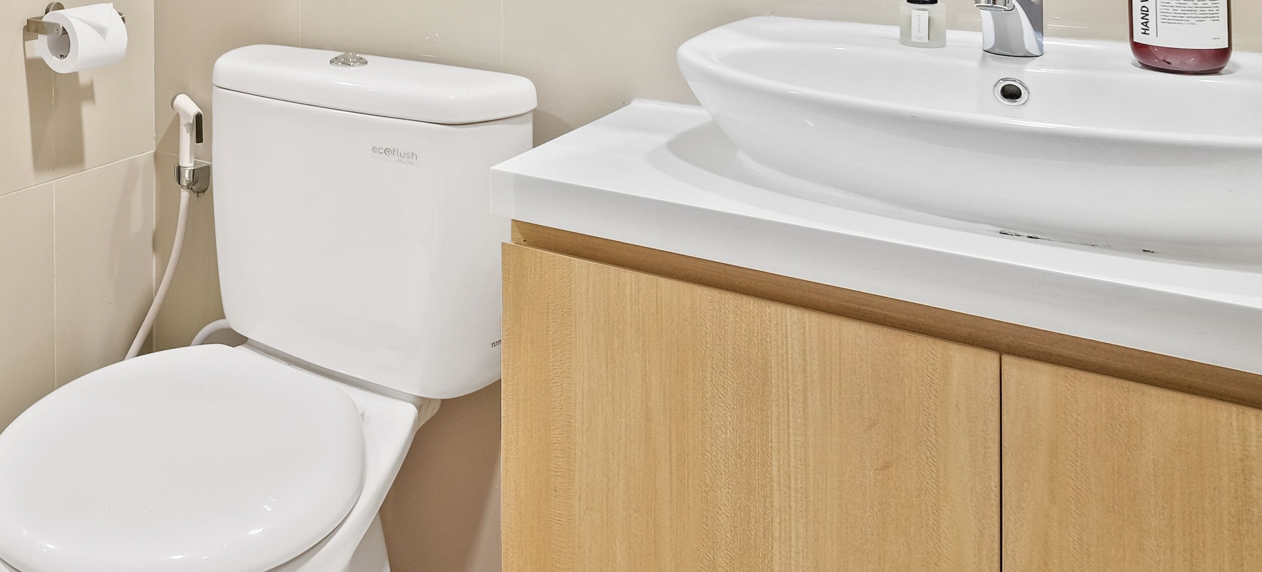 A bathroom with a toilet, sink, and wooden cabinet.