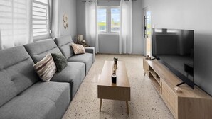 Un salon moderne avec un canapé gris, une table basse en bois et un téléviseur à écran plat.