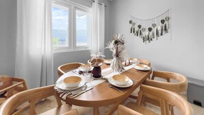 Un coin repas avec une table ronde en bois, dressée pour quatre personnes, entourée de chaises en bois.