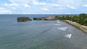 A coastal landscape with clear skies, calm sea, and rocky formations. - Casa La Cueva Apt 2 | Boho Oceantfront House (Arecibo)