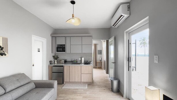 A modern kitchen with a central island, a grey sofa, and a lamp on a side table. - Casa La Cueva Apt 2 | Boho Oceantfront House (Arecibo)