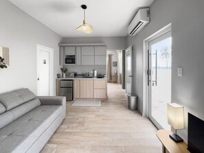 Een moderne keuken met een centraal eiland, een grijze bank en een lamp op een bijzettafeltje.