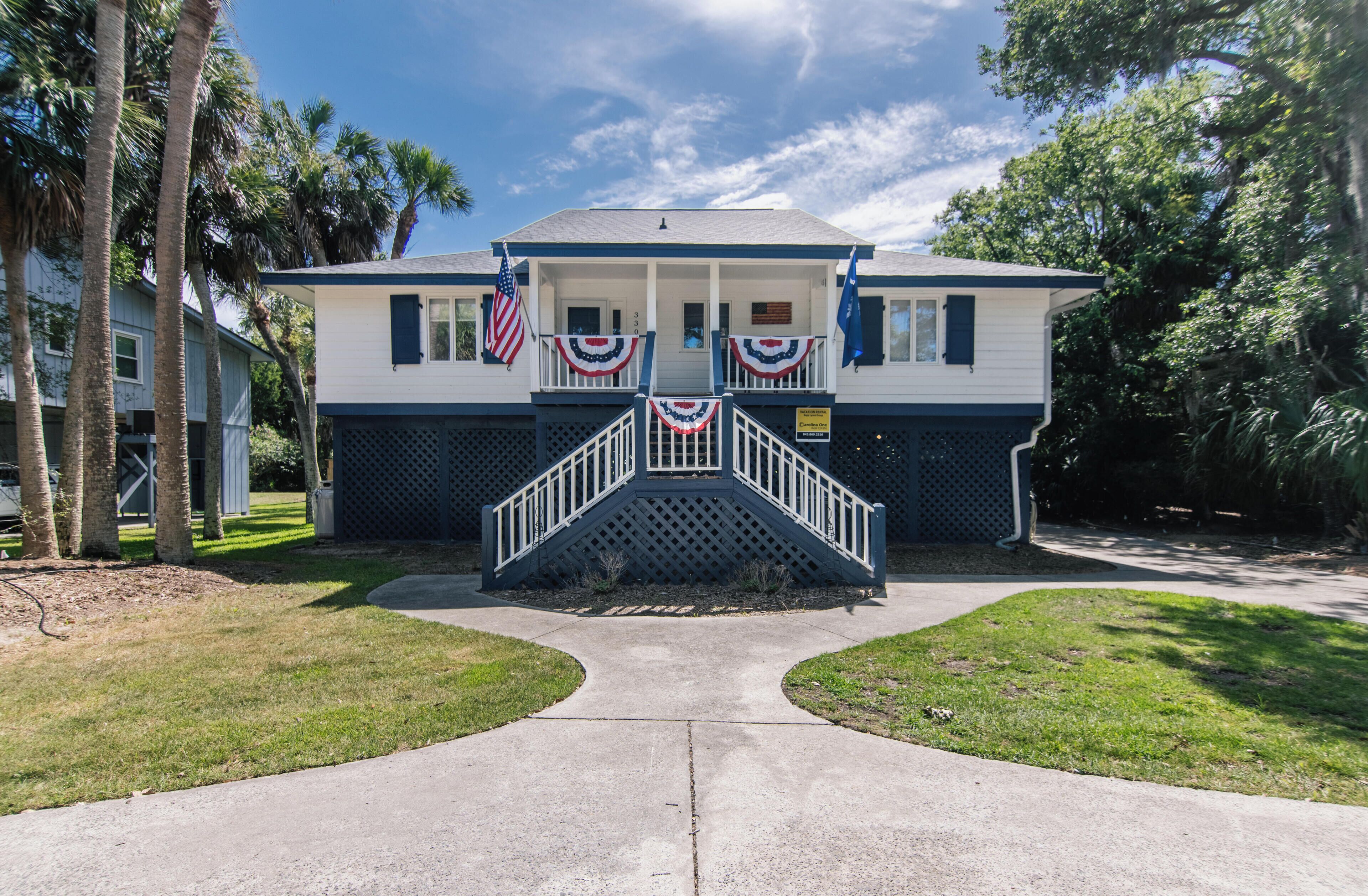 A two-story building with a porch, American flags, and a sign indicating it is a historical site.