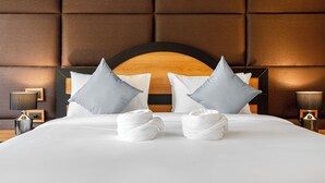Una cama bien hecha con sábanas blancas, dos almohadas y dos toallas dobladas al pie de la cama.
