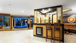 Un interior moderno con una zona de bar, asientos y vistas a una piscina exterior.