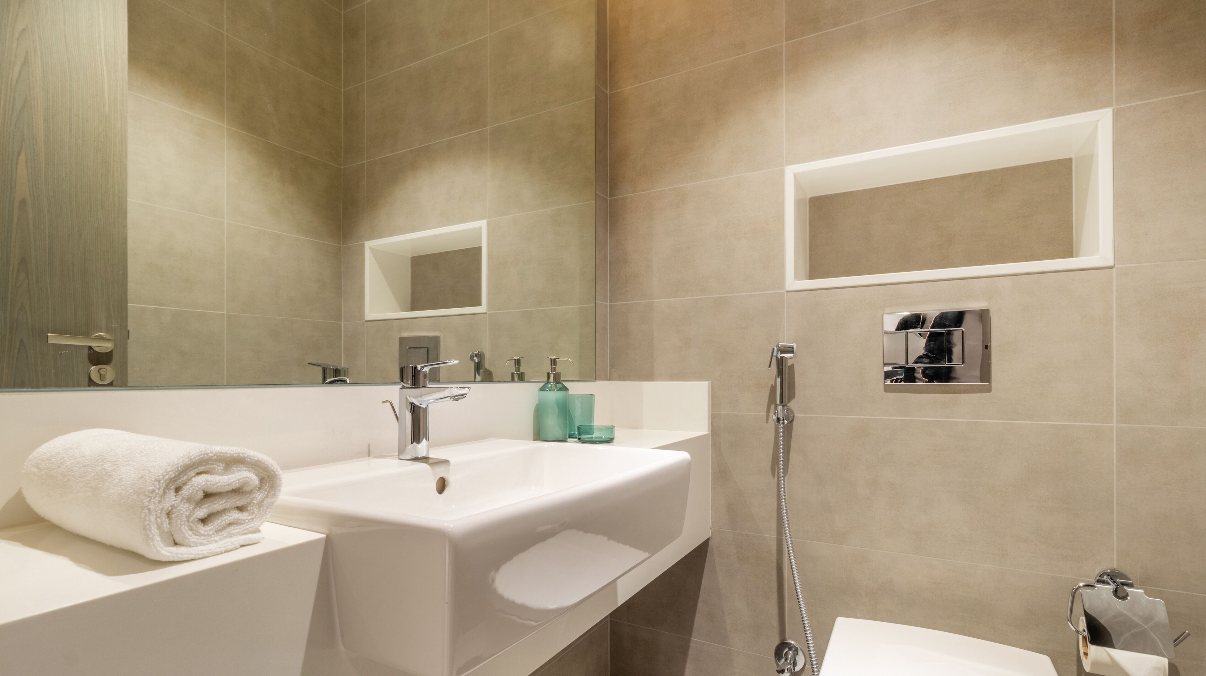 A modern bathroom with a large sink, mirror, and shower.