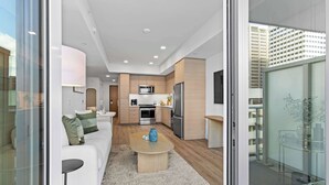 A modern apartment with a living area, kitchen, and a balcony with a glass door.