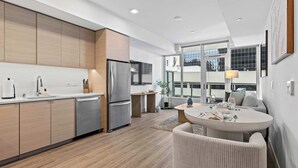 A modern kitchen with wooden cabinets, stainless steel appliances, and a dining area with a round table and chairs.