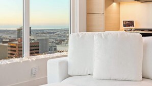 A modern bedroom with a large window, a white sofa, and a view of the cityscape. - Luxury 39th-Floor Sky Residence · Ocean Views (San Diego)