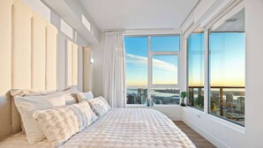 A modern bedroom with a large bed, city view, and large windows. - Luxury 39th-Floor Sky Residence · Ocean Views (San Diego)