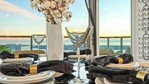 A table set for a meal with a view of a bridge and cityscape. - Luxury 39th-Floor Sky Residence · Ocean Views (San Diego)
