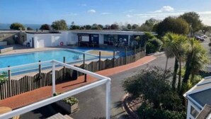 A pool area with a wooden deck and a white fence. - Beverley bay 2-Bed Caravan, Sleeps 6, Pet Friendly (Paignton)