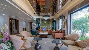 A spacious lobby with modern furniture, a chandelier, and large windows offering a view of greenery. - Chokar Dhani Resort (Kalmeshwar)
