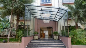 A modern hotel entrance with a glass canopy, a red carpet, and a staircase leading to the lobby. - Chokar Dhani Resort (Kalmeshwar)