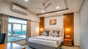 A modern hotel room with a large bed, a desk, and a view of the outdoors. - Chokar Dhani Resort (Kalmeshwar)