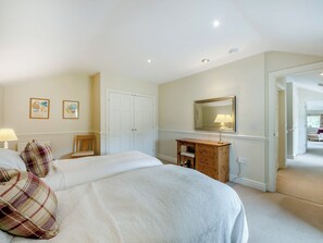 Un dormitorio con dos camas, un aparador, un espejo y una puerta que da a otra habitación.