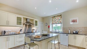 Een moderne keuken met een centraal eiland, roestvrijstalen apparatuur en een raam met uitzicht op bloemen.