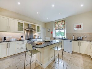 A modern kitchen with a central island, stainless steel appliances, and a window with a floral view.
