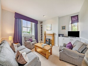 A living room with a fireplace, sofa, coffee table, and television.