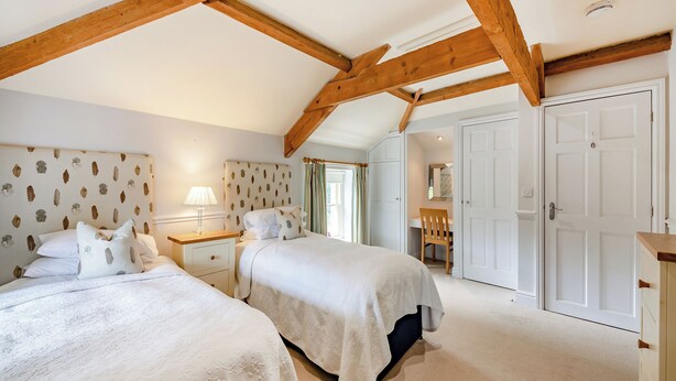 Een slaapkamer met twee bedden, een bureau, een stoel en een kledingkast.