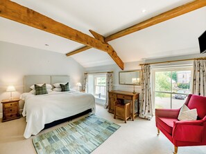 Een slaapkamer met een bed, bureau, stoel en uitzicht op buiten.