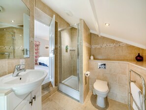 Een moderne badkamer met een douchecabine van glas, een witte wastafel en een toilet.