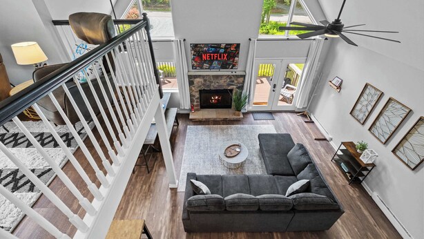 Ein modernes Wohnzimmer mit Kamin, grauem Sofa und Deckenventilator.