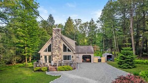 Ein zweigeschossiges Haus mit einem Steinsschornstein, einer Veranda und einer Garage.