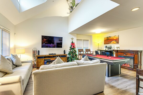 Amplia sala de estar con mesa de billar, sofá y árbol de Navidad.