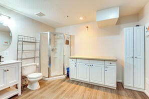 Un baño con inodoro, cabina de ducha, tocador con armarios y espejo.
