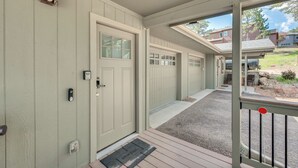 En overdækket veranda med dør, garage og indkørsel til et hus.