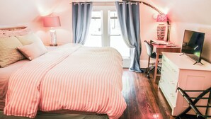 Una camera da letto con un letto, una scrivania, una televisione e un comò.