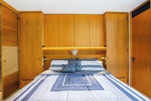 Un dormitorio con una cama grande, un armario de madera y una mesita de noche.
