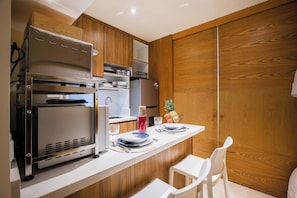 A compact kitchen with built-in appliances, a small dining area, and wooden cabinetry.