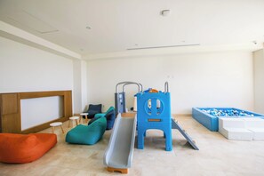 Zona de juegos infantiles con tobogán, estructura de juego y piscina de pelotas.