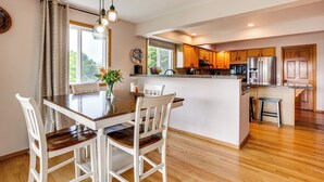 Una cocina moderna con armarios de madera, una isla central y un comedor con mesa y sillas de madera.