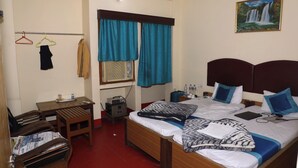 A hotel room with a bed, a desk, a chair, a TV, and a painting on the wall. - Hotel Laxmi Inn (Patna)