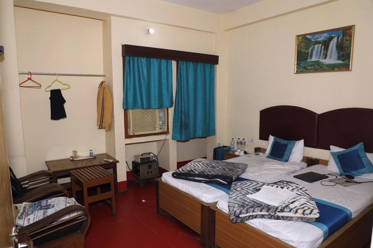 A hotel room with a bed, a desk, a chair, a TV, and a painting on the wall.