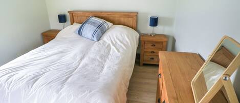 A bedroom with a wooden bed, two bedside tables, a dresser, and a mirror.