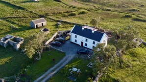 An aerial view of a rural property with a white house, a stone building, and a small dock. - NEAD NA BHFÁINLEOG (SWALLOWS’ NEST) in Claddaghduff, County Galway (Clifton)