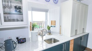 A modern kitchen with a large window, a sink, and cabinets. - NEAD NA BHFÁINLEOG (SWALLOWS’ NEST) in Claddaghduff, County Galway (Clifton)